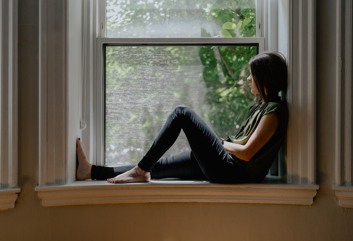 Woman sitting on a window sill in peaceful natural light