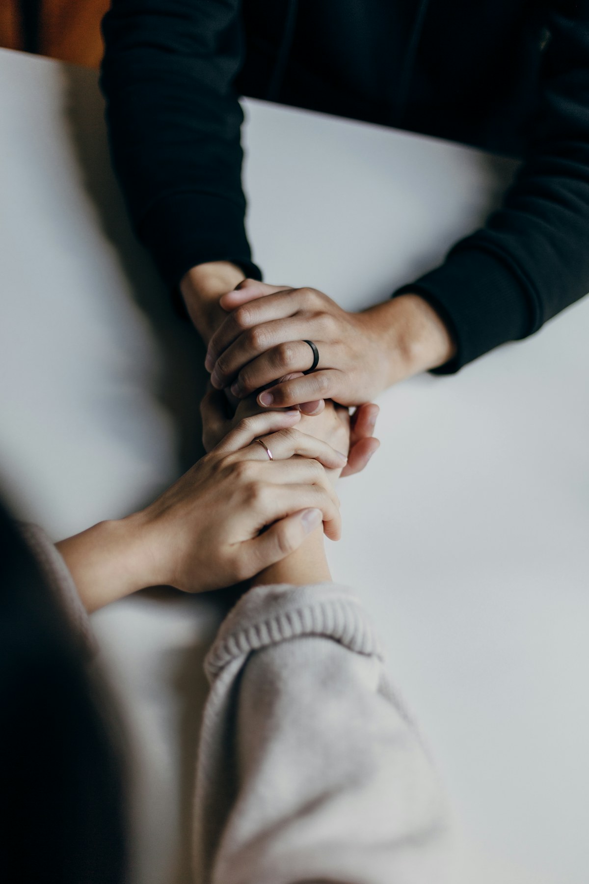Two people sitting at a table, one offering a comforting hand to the other