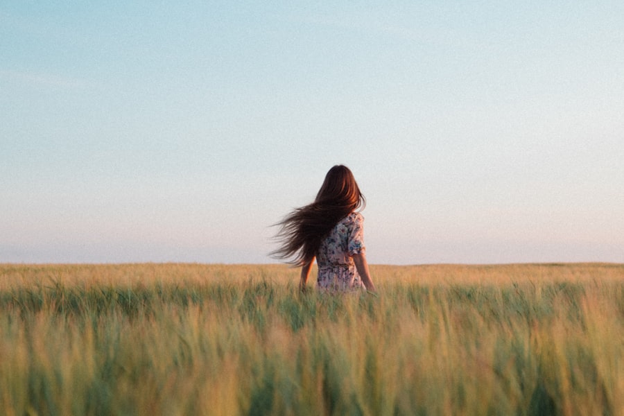 Woman standing in a tall grassy field under a soft sky