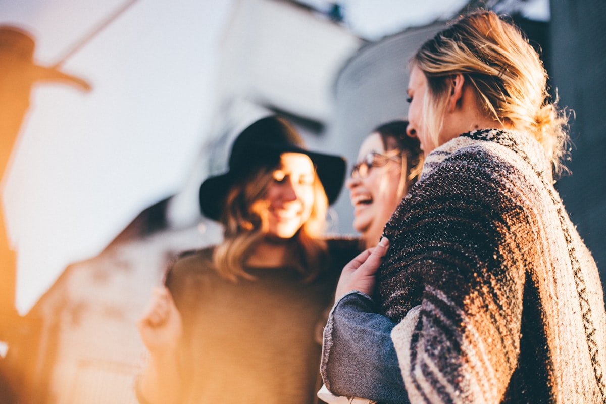 Group of people laughing and connecting outdoors in warm daylight