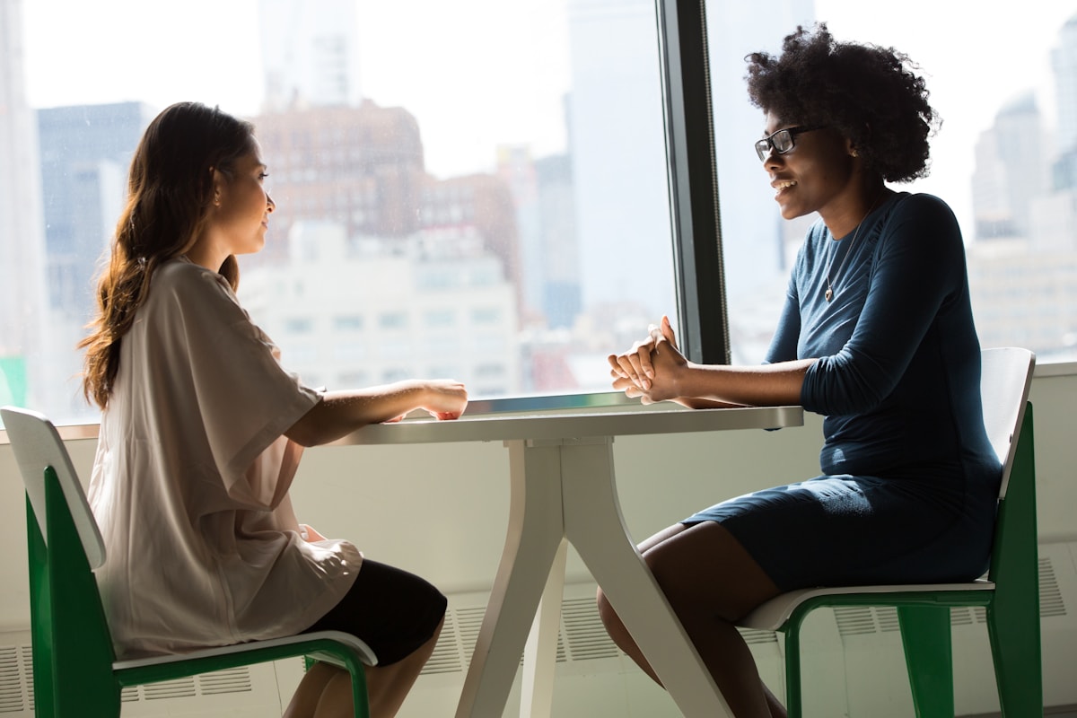 Two women sitting at a table, engaged in a warm professional conversation